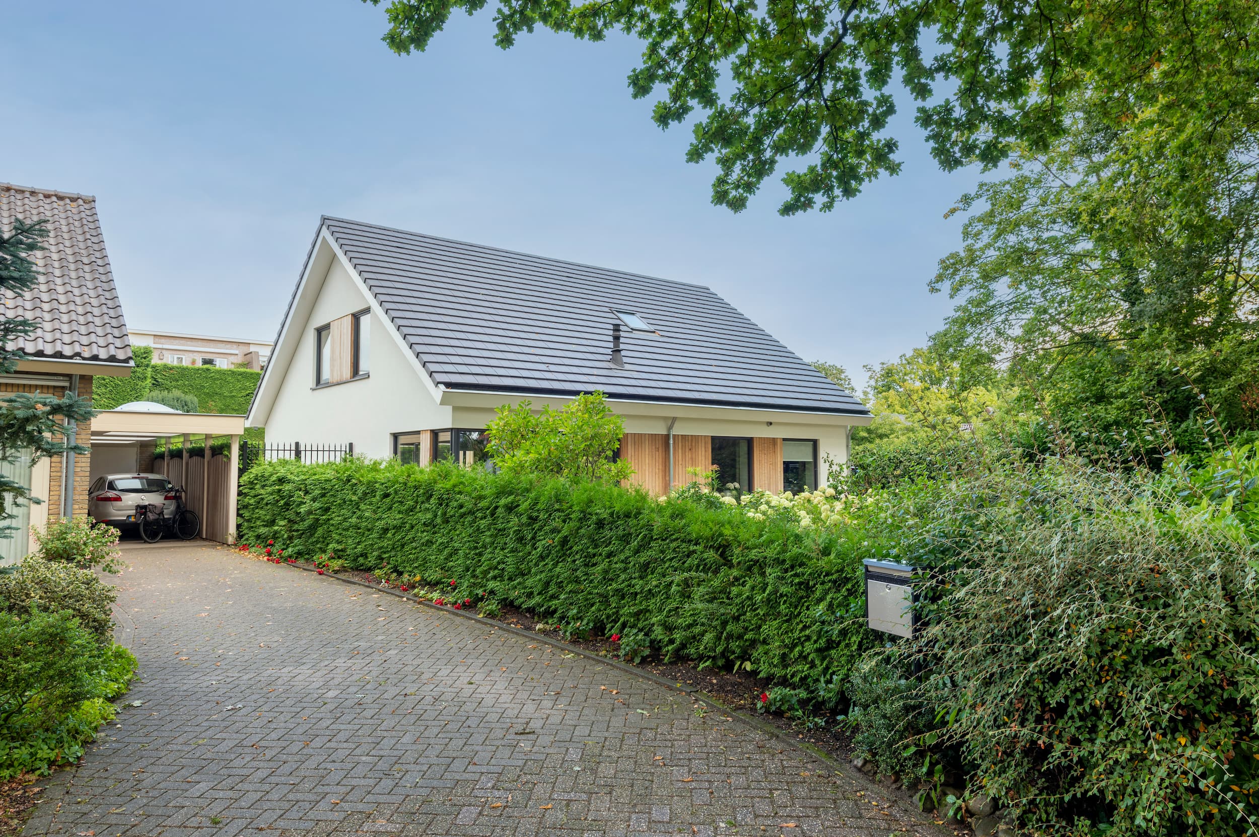 Transformatie van een bungalow tot duurzame, moderne woning. Ontdek het tijdloze ontwerp met strak wit stucwerk en warme houten gevelaccenten.